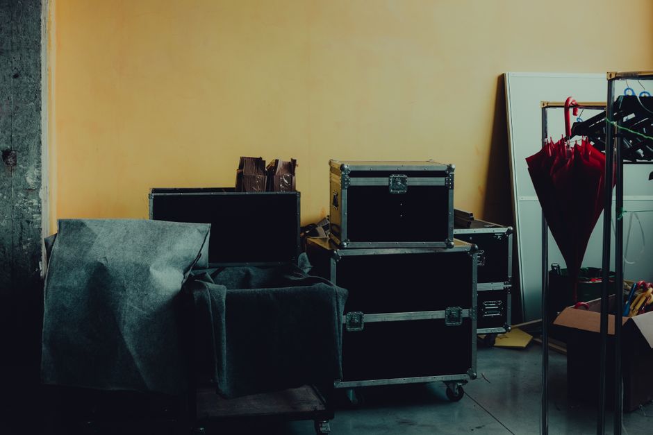 Many boxes and huge iron cases near umbrella placed in room with yellow walls