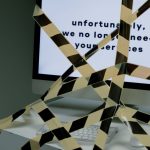 A computer screen taped and displaying a termination message, symbolizing unemployment.