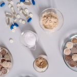 High-angle shot of various pharmaceutical ingredients and pills on a white surface. Ideal for healthcare and science themes.
