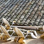 A row of satellite dishes set against an intricately tiled roof, depicting modern technology blending with traditional architecture.