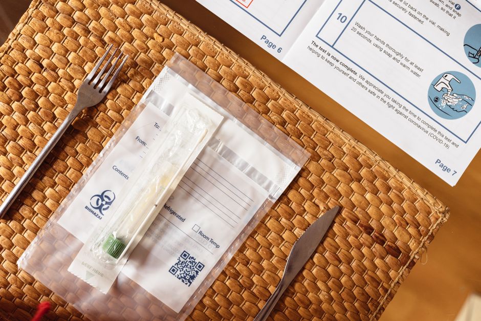 A COVID-19 test kit arranged on a woven table mat beside cutlery, highlighting healthcare at home.