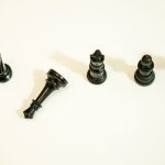Overhead shot of black chess pieces on a white surface, symbolizing strategy and intellect.