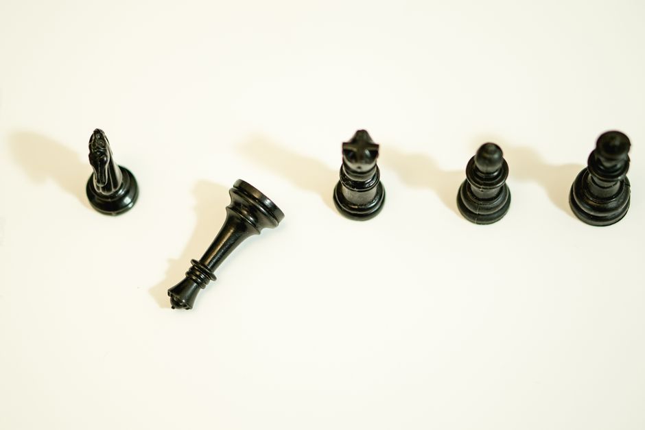 Overhead shot of black chess pieces on a white surface, symbolizing strategy and intellect.
