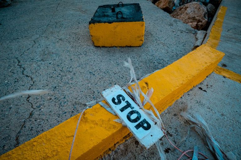 Close-up of a weathered stop sign on a yellow-painted curb, conveying caution.