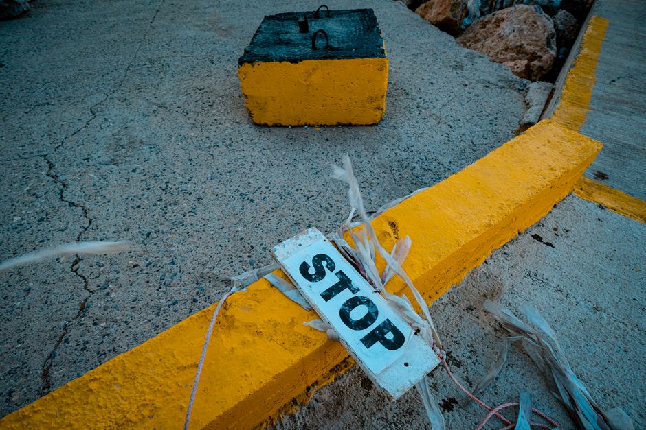 Close-up of a weathered stop sign on a yellow-painted curb, conveying caution.