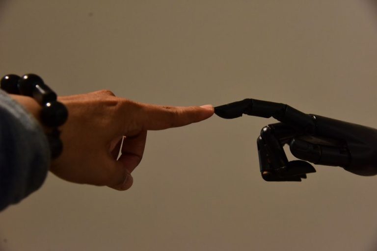 A human hand and a robotic hand extending fingers to touch, symbolizing connection.