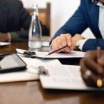 Business meeting with adults discussing and signing contracts over a table.