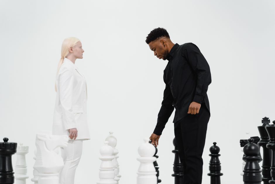 Two adults strategizing with oversized chess pieces, emphasizing competition and intellect.
