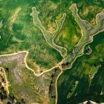 Stunning aerial view of lush green fields and winding paths in a countryside landscape.