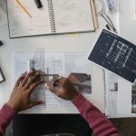 Incentive Architecture: Designing Systems for High Performance Architect designing plans at a desk surrounded by tools, drafts, and blueprints.