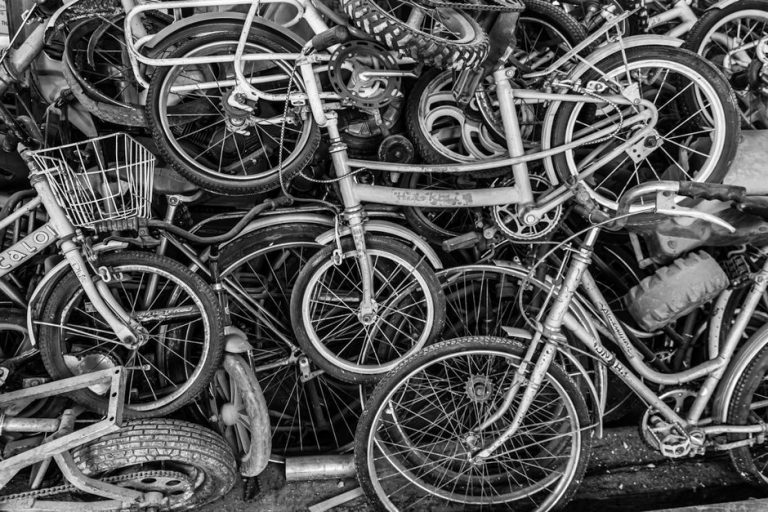 Chaotic pile of old bicycles in black and white, showcasing urban decay and recycling themes.