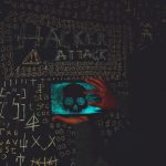 Information Warfare: Protecting Decision-Making from Noise A hacker in a black hoodie using a tablet displaying a skull, surrounded by chalk symbols and 'Hacker Attack' text.