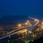 Infrastructure Longevity Optimization: A Guide for Leaders From above of glowing lamps on contemporary city road junction above greenery and broad river at night