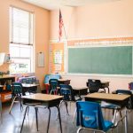 Institutional Resilience: Lessons from the 1285-1288 Crisis An inviting, sunlit classroom with empty desks and an American flag, ready for students.