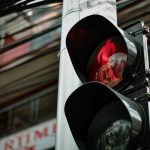 Close-up of a red pedestrian traffic light against a city background, capturing urban life.