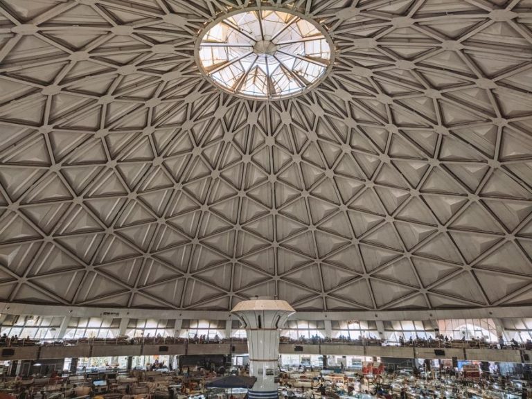 View of a geometric dome ceiling over a bustling indoor market space.