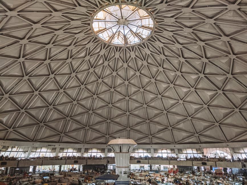 View of a geometric dome ceiling over a bustling indoor market space.