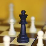 ISRU Strategy: Mastering Operational Autonomy and Efficiency A focused shot of a black king chess piece surrounded by white pawns on a chessboard.