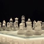 Close-up of a glass chess set with a reflection, emphasizing strategy and elegance.