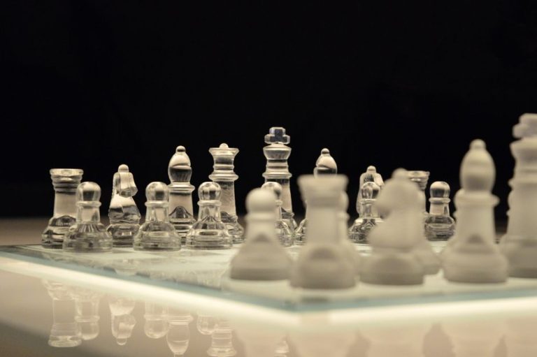 Close-up of a glass chess set with a reflection, emphasizing strategy and elegance.