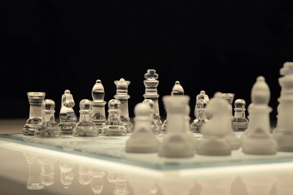 Close-up of a glass chess set with a reflection, emphasizing strategy and elegance.