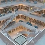 Explore the airy and geometric space of a modern library with intricate staircases and minimalist design.