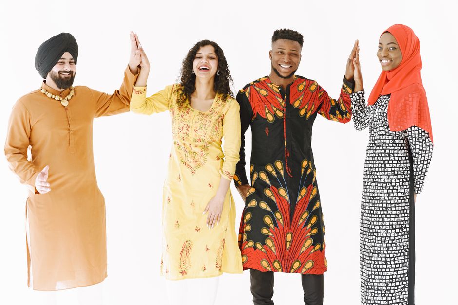 A joyful group of adults from diverse backgrounds high-fiving in traditional clothing.