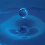 Liquid Governance: Replacing Static Models for Agile Success A high-speed capture of a water droplet splashing on a blue background, showcasing fluid dynamics.