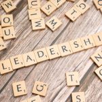 Wooden letter tiles spelling 'LEADERSHIP' on a wooden surface, symbolizing leadership qualities and skills.