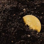 Golden Bitcoin partially buried in dark soil, symbolizing digital currency growth.
