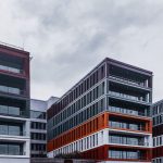 Contemporary office buildings with red and orange accents in an urban setting.