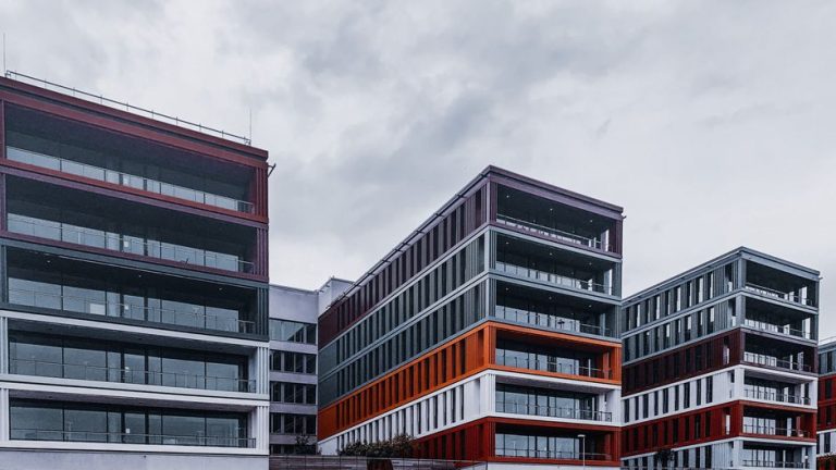 Contemporary office buildings with red and orange accents in an urban setting.