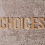 Wooden letters spelling 'choices' on a textured surface, symbolizing decision-making.