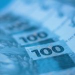Blurred close-up view of Brazilian 100 real banknotes, showcasing currency details.