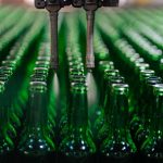 Manufacturing Automation Strategy: Avoiding Common Pitfalls Rows of green glass bottles on an automated production line in a factory setting.