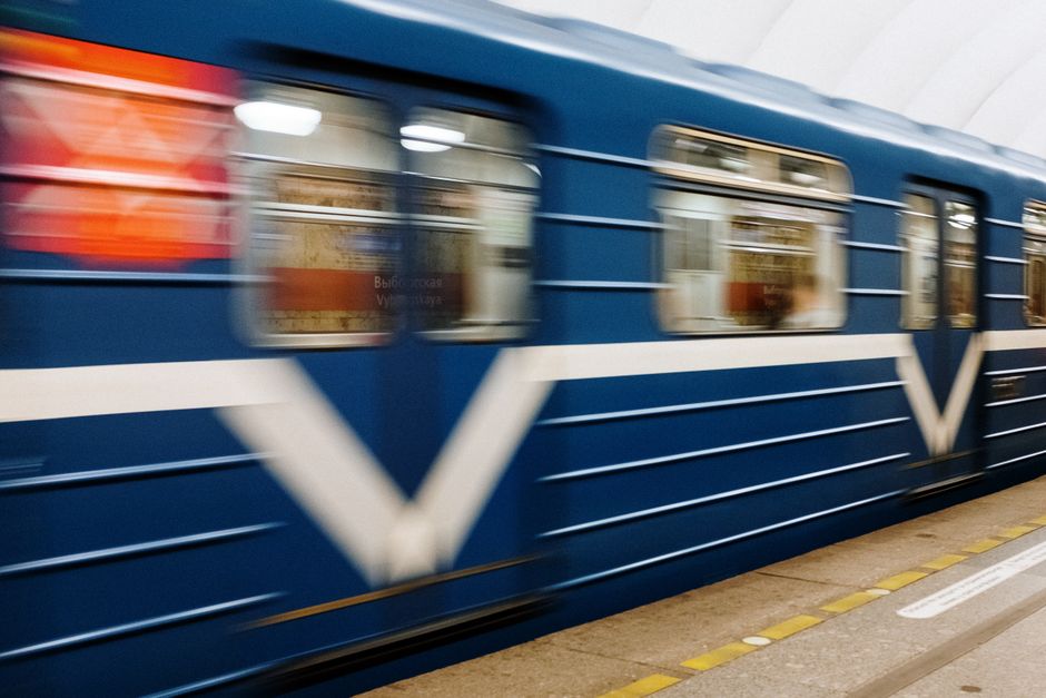 A motion blur capture of a blue subway train speeding through an underground station.