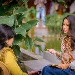 Master Interpersonal Communication as a High-Leverage Strategy Two women sitting near lush plants having a conversation outdoors. Relaxed and candid atmosphere.