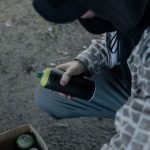 A graffiti artist holding a spray paint can outdoors, preparing to create street art.