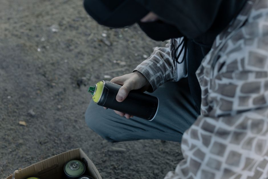 A graffiti artist holding a spray paint can outdoors, preparing to create street art.