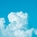Bright cumulus clouds floating in a clear blue sky, capturing a sunny summer day.