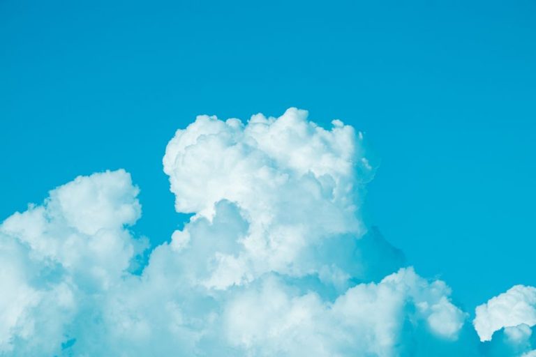Bright cumulus clouds floating in a clear blue sky, capturing a sunny summer day.