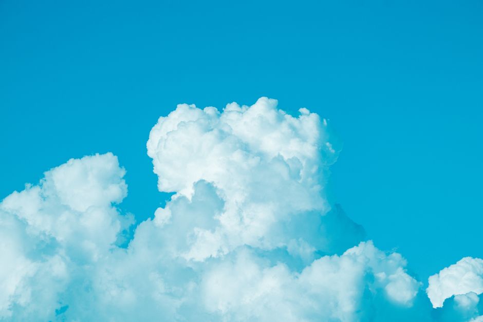 Bright cumulus clouds floating in a clear blue sky, capturing a sunny summer day.