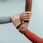 Mastering Global Interdependence: A Guide for Modern Leaders Three individuals' hands connected in a symbol of teamwork and diversity.