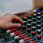 A close-up of a hand adjusting knobs on an audio mixer for precise sound control.