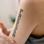 A close-up view of a 'Freedom' tattoo on a woman's arm, symbolizing independence and strength.