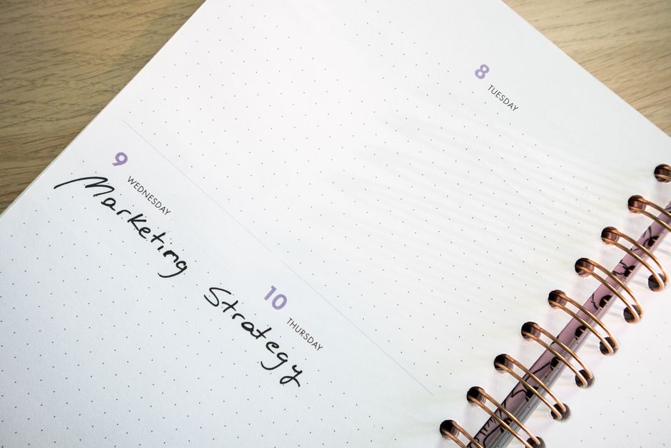 Detailed spiral-bound planner showing marketing strategy notes. Perfect for time management themes.