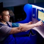Mental Health Monitoring AI: Predictive Tools for Leadership A man uses a touch screen for a telemedicine health check in a modern setting.