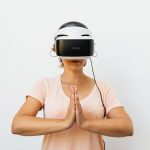 Mind Uploading and the Future of Strategic Cognitive Systems Adult woman practicing meditation with a virtual reality headset against a white background.
