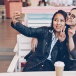 Two young women capturing a fun selfie moment in a stylish cafe setting.