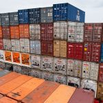 Colorful stacked shipping containers on a cargo ship traveling at sea, showcasing global trade.